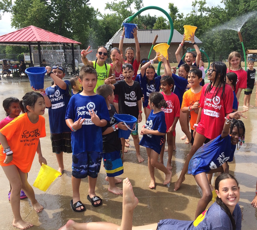 Group of campers and counselors smiling and posing at splashpad