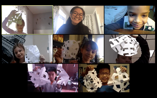 Group of campers and instructor smiling and showing their snowflake crafts on a video call during our virtual French class